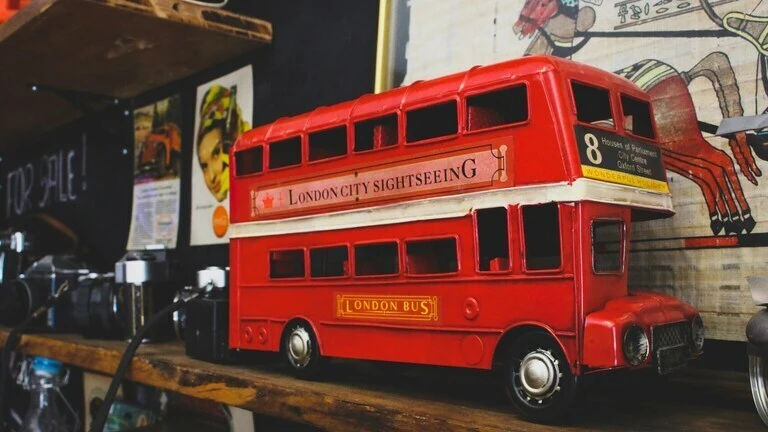 Vintage red London double-decker bus toy on a wooden shelf