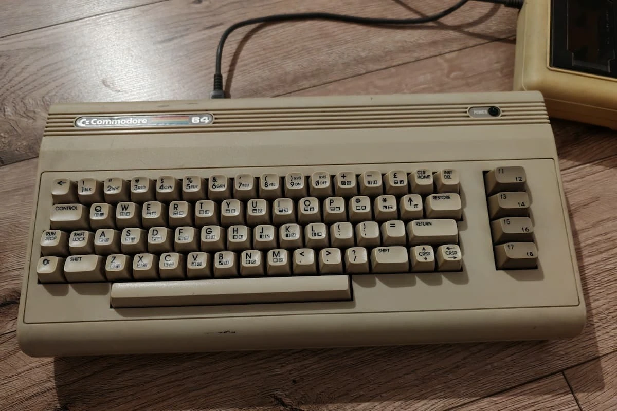 Commodore 64 computer on a wooden floor, showing the classic keyboard used for retro games and programs