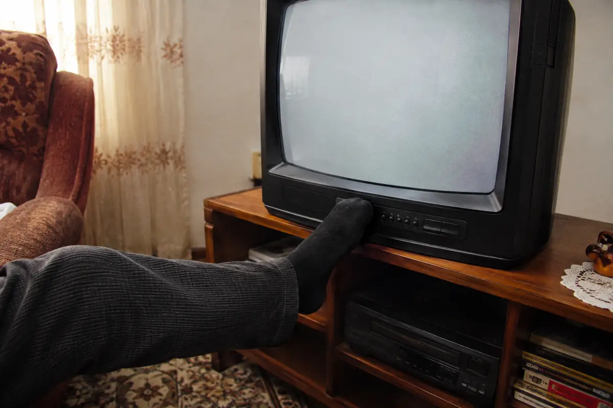 Changing the channel with a foot in a scene inspired by 90s TV memories