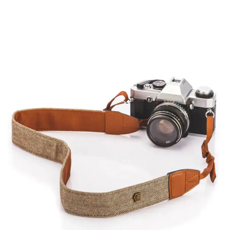 Brown and beige retro camera strap attached to a vintage film camera