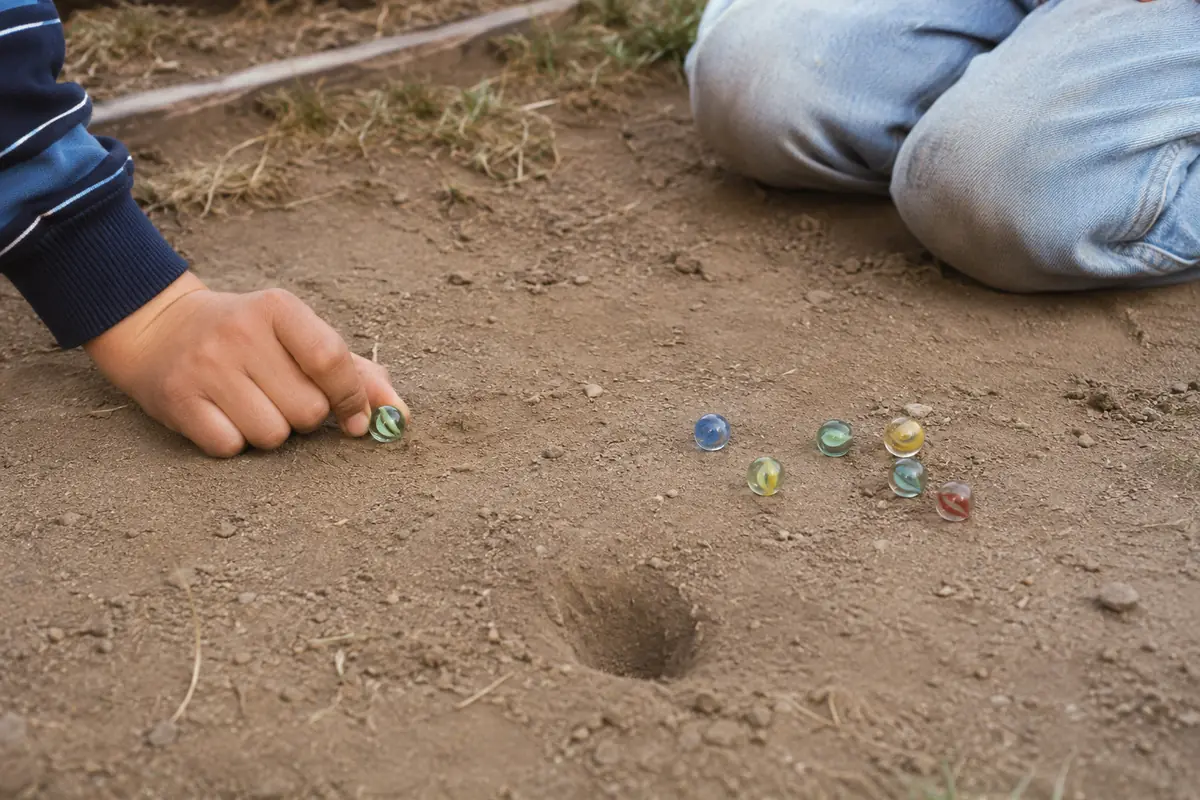 Child aiming a glass marble in one of the outdoor games played before smartphones