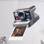 Polaroid Mod instant camera with a photograph emerging, shown in a studio