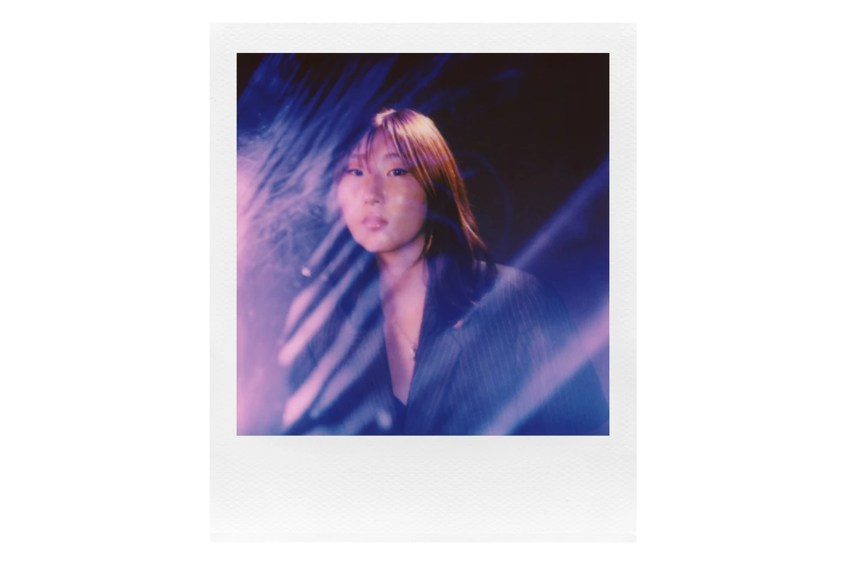 Instant portrait of a woman with blue and purple light trails inside a white Polaroid border
